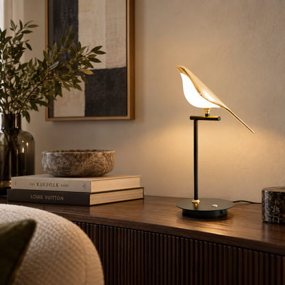 Avelle single bird table lamp lit on a dark wood surface beside a vase