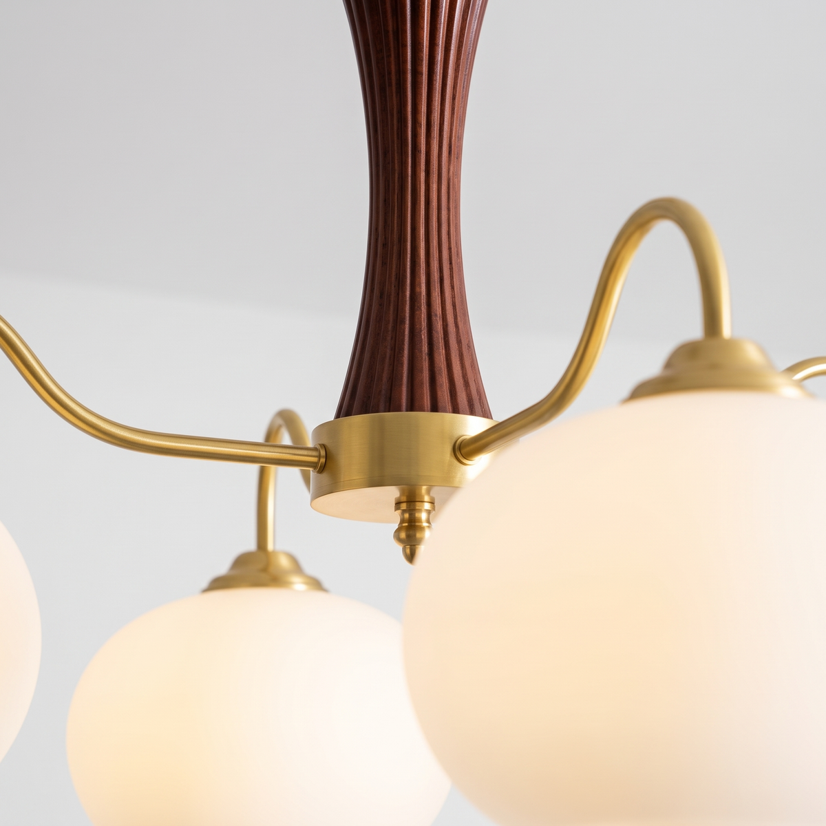 Close-up of Cassius walnut stem, brass arms and opal glass