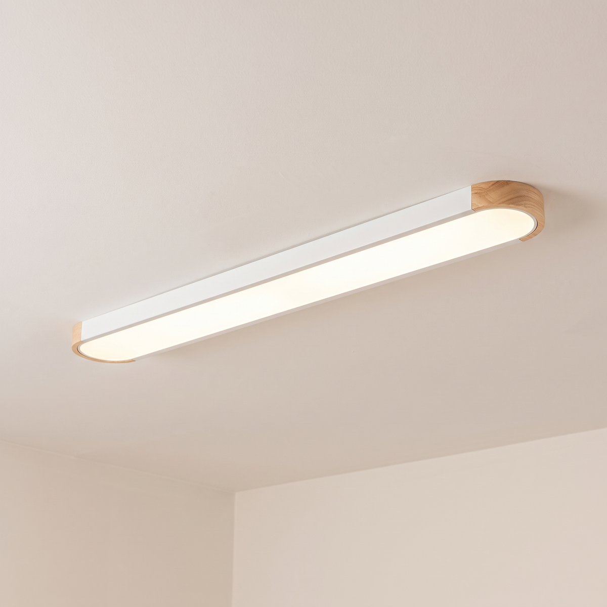 Imogen oval LED ceiling light, white 122 cm, oak wood ends, warm light on a white ceiling