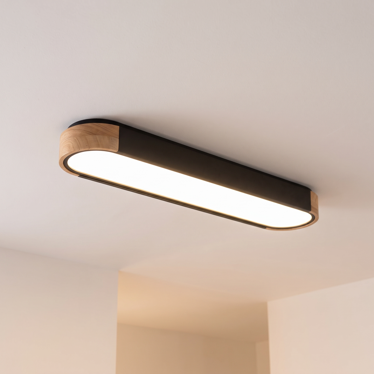 Imogen oval LED ceiling light, black 95 cm, oak wood ends, warm light on a white ceiling
