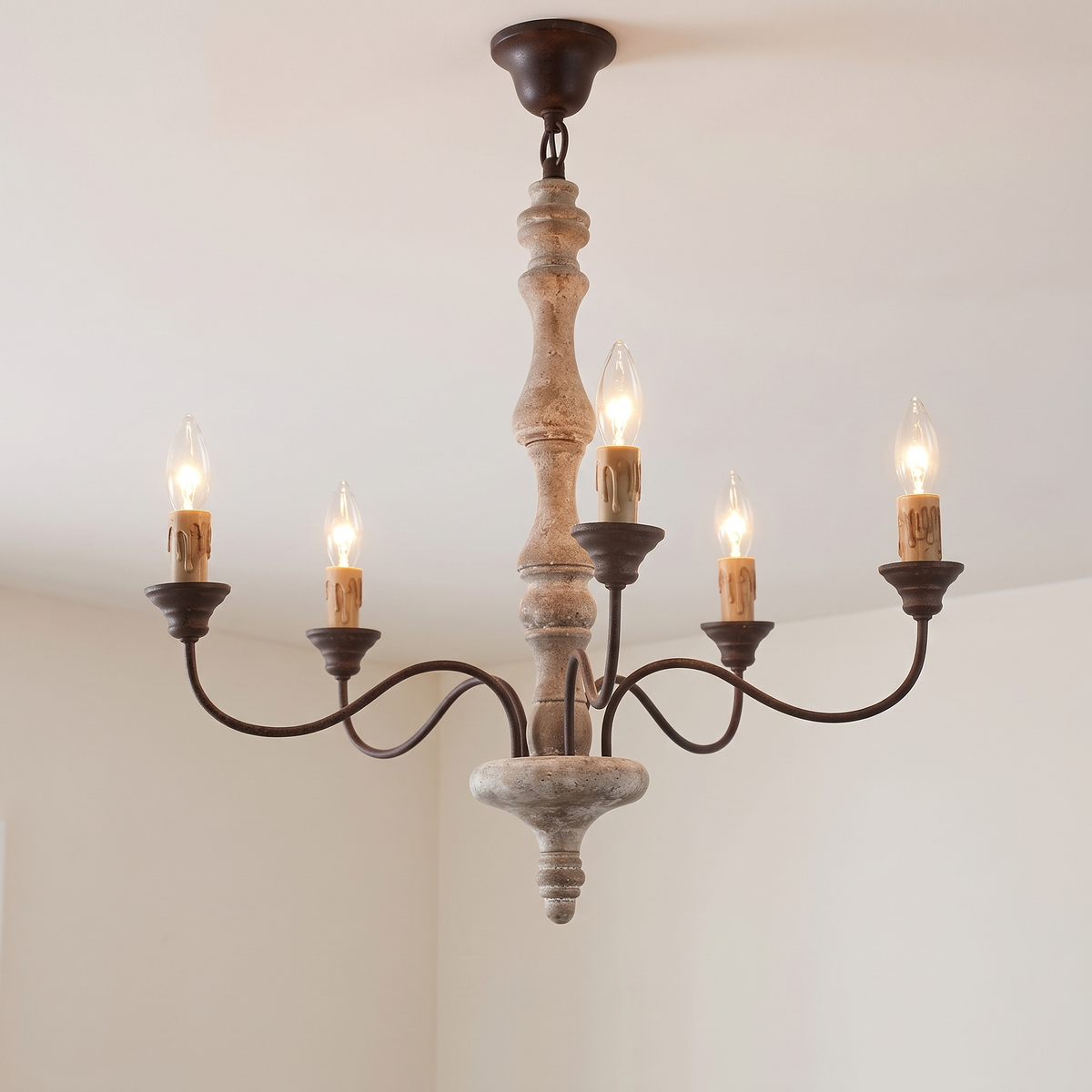 Amalia rustic candle chandelier, 5-light with brown candles, lit, hanging from a white ceiling
