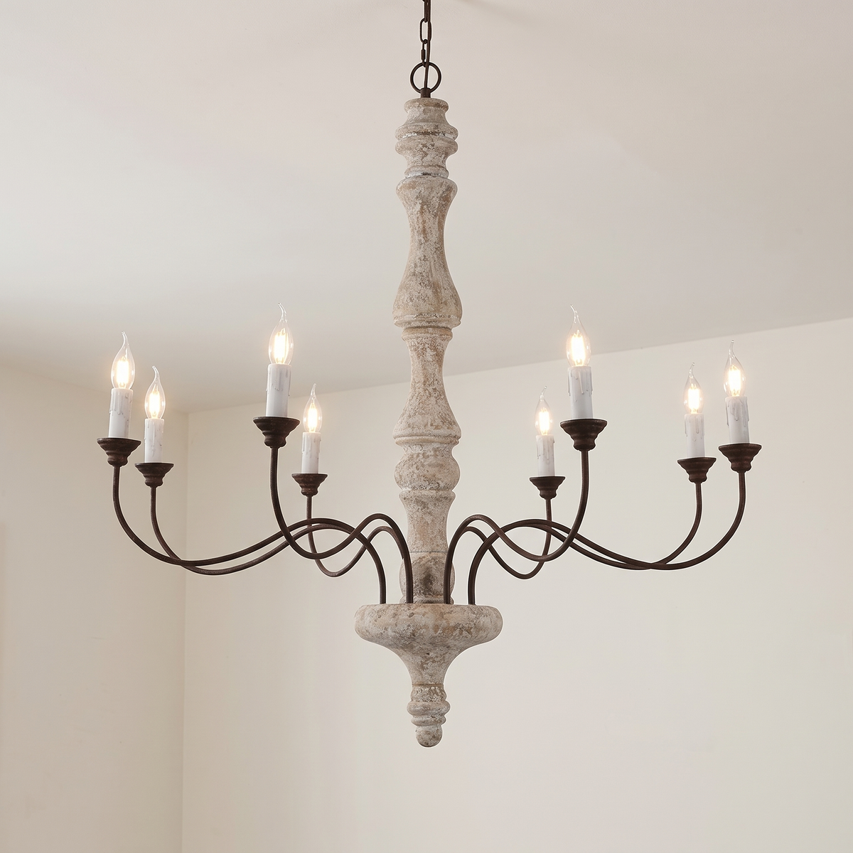 Amalia rustic candle chandelier, 8-light with white candles, lit, hanging from a white ceiling