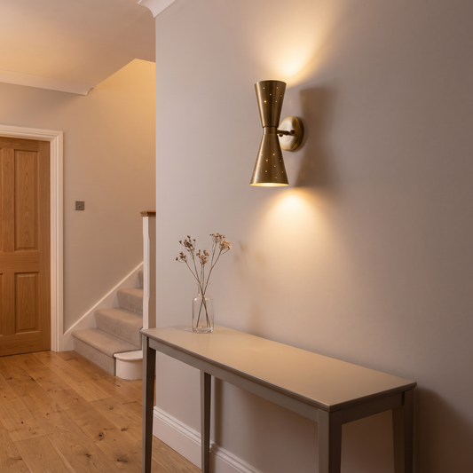 Stellan brass hourglass wall light – glowing in a hallway