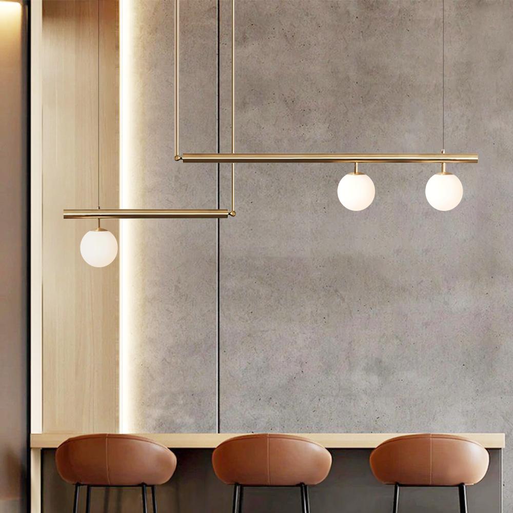 Vittoria linear chandelier – in brass against a concrete wall