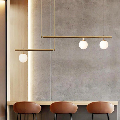 Vittoria linear chandelier – in brass against a concrete wall
