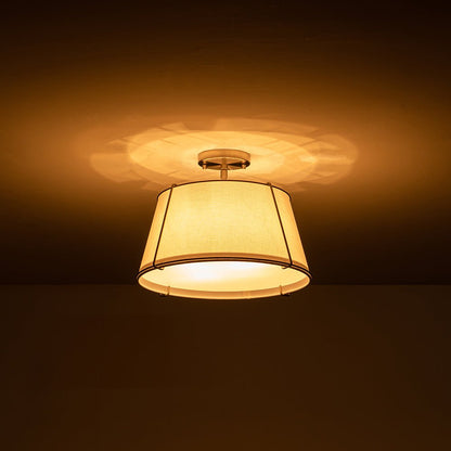Theodora tapered drum ceiling light – lit with a warm glow
