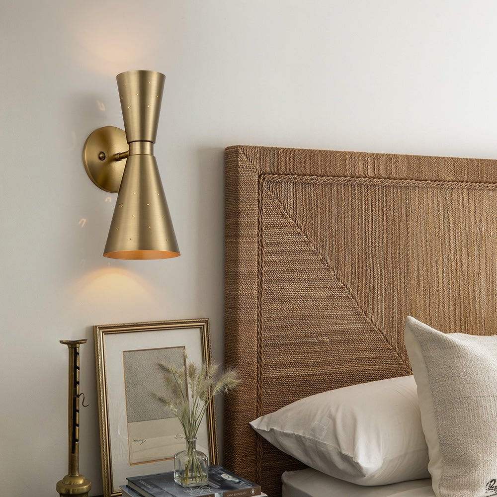 Stellan hourglass wall light – in brass in a bedroom, alternate view