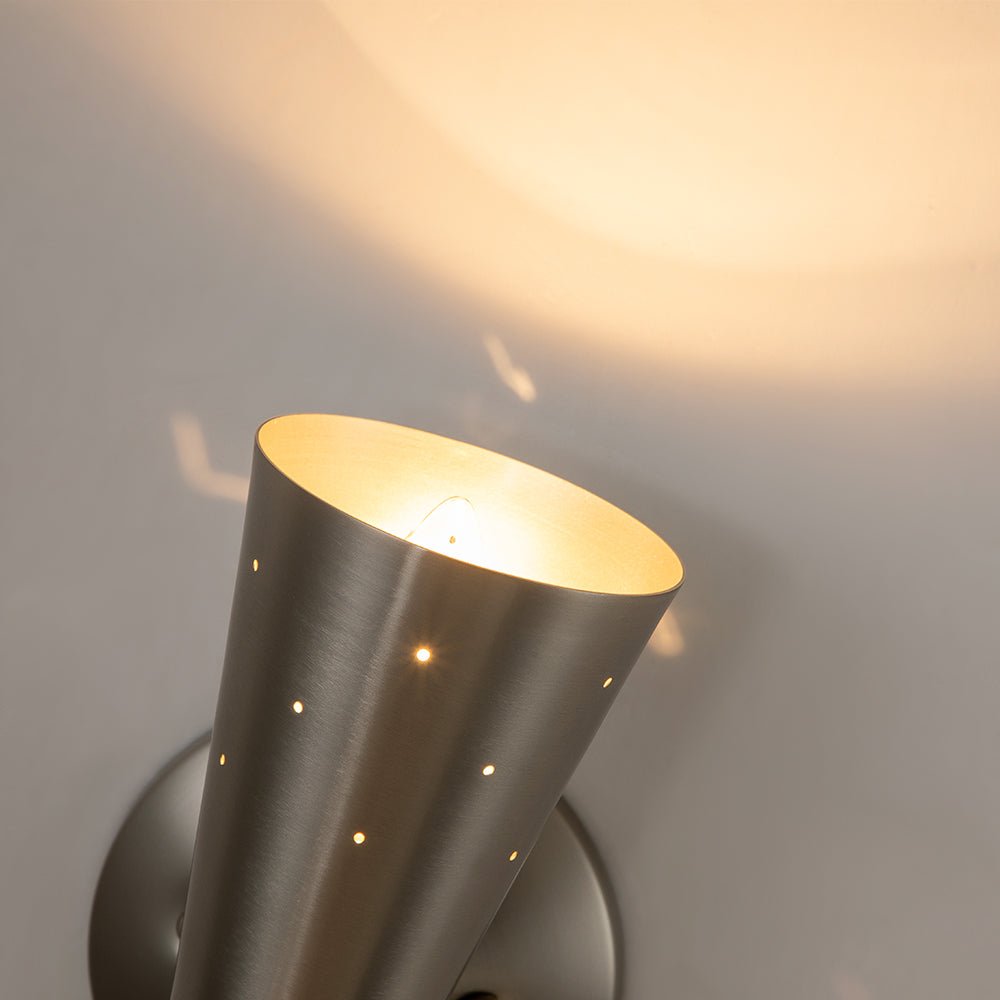 Stellan hourglass wall light – in nickel, lit on a wall