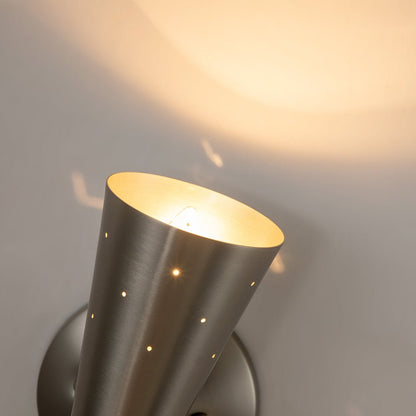 Stellan hourglass wall light – in nickel, lit on a wall