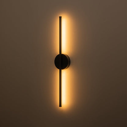 Sebastian linear LED wall light – in black, lit on a brown wall