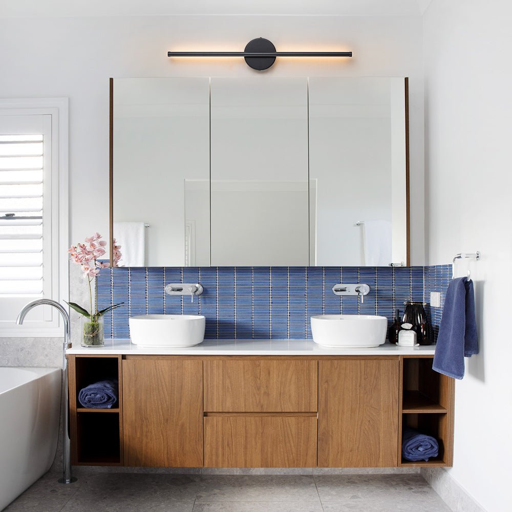 Sebastian linear LED wall light – in black above a bathroom mirror