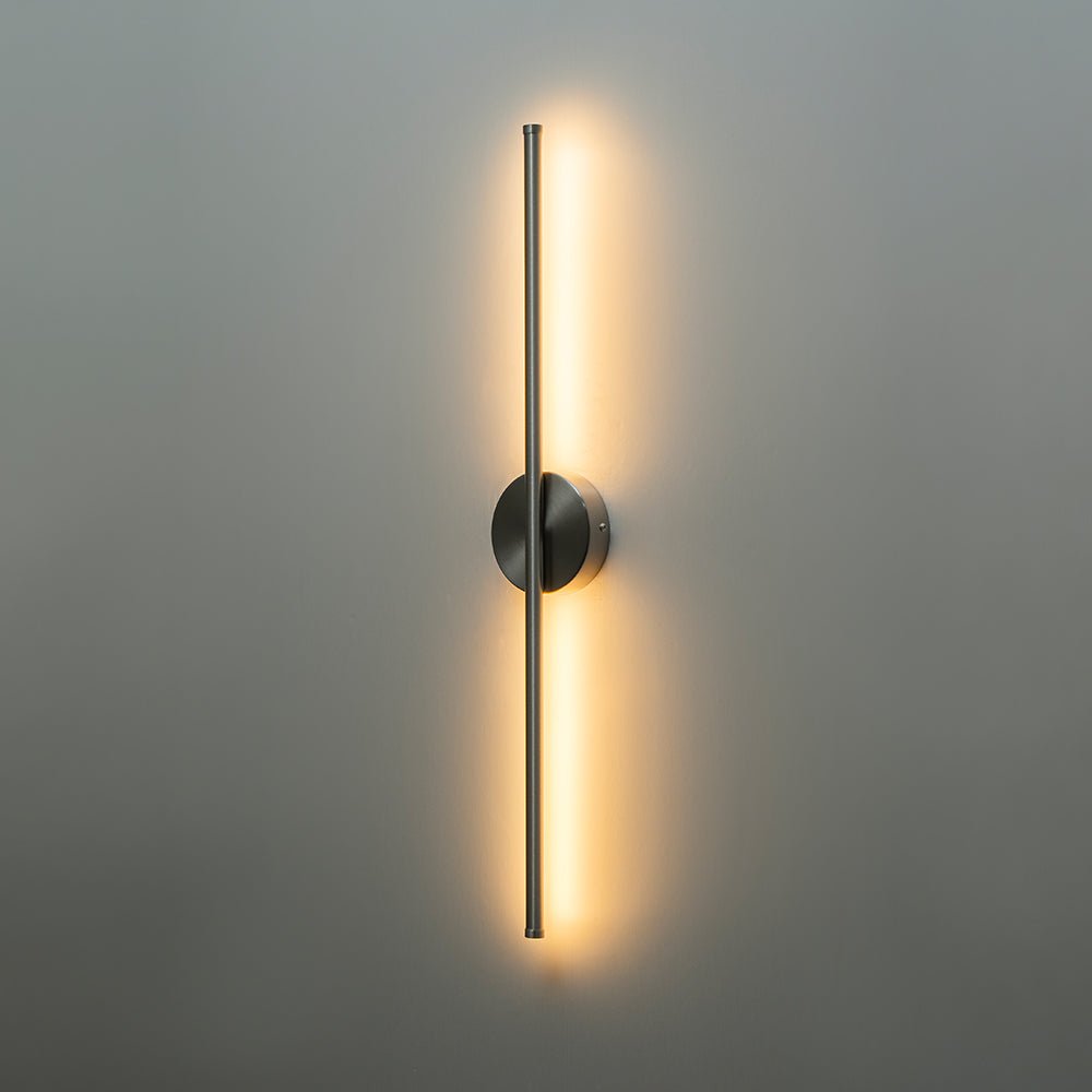 Sebastian linear LED wall light – in nickel, lit on a grey wall